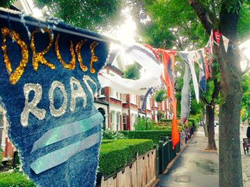 Close up of bunting hanging from a tree with houses in the back.